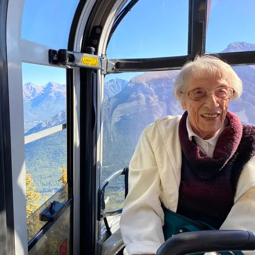 Senior woman riding on a sight seeing cable car with a big smile / Femme âgée à bord d'un téléphérique panoramique avec un grand sourire